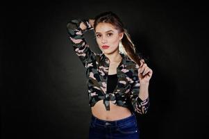 belle fille brune porte une chemise militaire et un jean, posant au studio sur fond gris. portrait de modèle de studio. photo