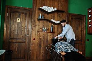 bel homme barbu au salon de coiffure, coiffeur au travail. tête de lavage. photo