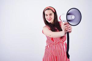 portrait d'une belle jeune femme en robe rouge parlant dans un mégaphone. photo