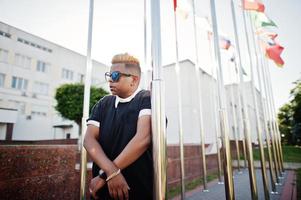 garçon musulman arabe élégant avec des cheveux à l'origine posés dans les rues, contre des drapeaux de différents pays. photo