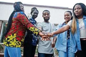 groupe de cinq étudiants africains qui passent du temps ensemble sur le campus de la cour universitaire. amis afro noirs qui étudient. thème de l'éducation. mains sur les mains. photo