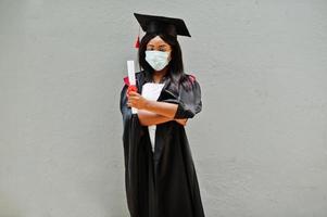 une jeune étudiante diplômée afro-américaine porte un masque de protection contre le coronavirus. concept de cérémonie de remise des diplômes, quarantaine. photo