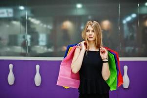 fille avec des sacs à provisions dans le centre commercial contre le mur du club de bowling. photo