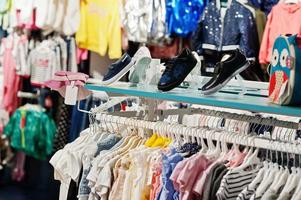 des vêtements lumineux pour enfants sont accrochés à l'écran du magasin de vêtements pour bébés. rubrique filles. photo