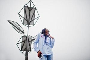 fille afro-américaine élégante avec des dreads tenant un téléphone portable à portée de main, en plein air contre des batteries solaires par temps de neige. photo