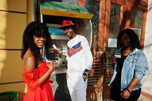 groupe de trois amis afro france élégants et branchés posés contre un distributeur automatique. modèle d'homme africain noir avec deux femmes à la peau foncée avec cartes de crédit. photo