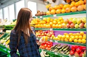 femme commerçante regardant les étagères du supermarché. portrait d'une jeune fille dans un magasin de marché au rayon fruits et légumes. photo