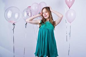 fille heureuse en robe turquoise verte avec des ballons colorés isolés sur blanc. célébrer le thème de l'anniversaire. photo