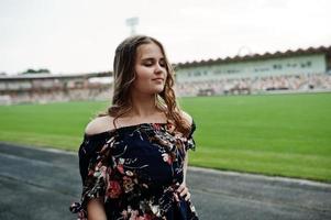 portrait d'une fille fabuleuse en robe et talons hauts sur la piste du stade. photo