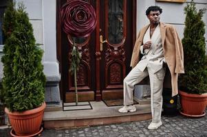 homme afro élégant en costume et manteau beige old school. jeune homme africain à la mode en veste décontractée sur torse nu. photo