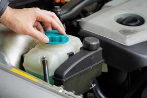 le mécanicien inspecte le vase d'expansion avec de l'antigel vert. niveau de liquide de refroidissement du véhicule dans le système de radiateur de la voiture. pièces automobiles photo