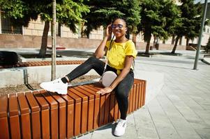 portrait d'une femme afro-américaine noire en t-shirt jaune et lunettes. photo