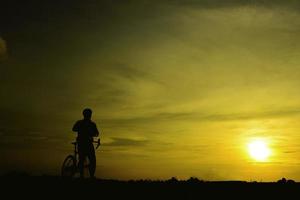 silhouette d'un bel homme faisant du vélo au coucher du soleil, concept d'homme sportif photo
