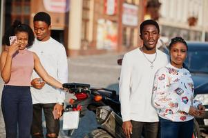 quatre amis africains marchant dans les rues contre la moto. photo
