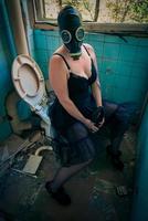femme avec masque à gaz sur les toilettes photo