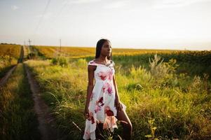 jolie jeune femme noire porte une robe d'été pose dans un champ de tournesol. photo
