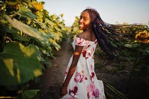 jolie jeune femme noire porte une robe d'été pose dans un champ de tournesol. photo