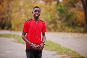 homme afro-américain en t-shirt de sport de football rouge contre le parc d'automne. photo