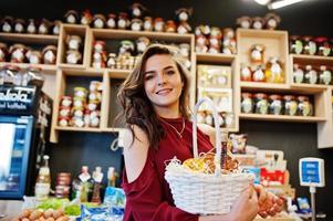 fille en rouge tenant différents produits sur le panier au magasin de charcuterie. photo