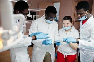 équipe de médecins dentistes multiraciale. trois médecins masculins afro-américains avec une femme médecin caucasienne. discussion des moments de travail. photo