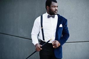 bel homme afro-américain à la mode en tenue de soirée et noeud papillon avec canne. photo