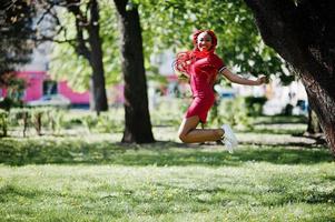 jolie et mince fille afro-américaine en robe rouge avec des dreadlocks saute en plein air dans le parc du printemps. modèle noir élégant. photo