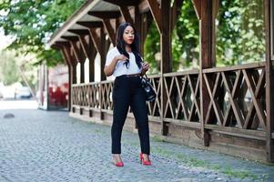 élégante femme d'affaires afro-américaine avec sac à main dans les rues de la ville. photo