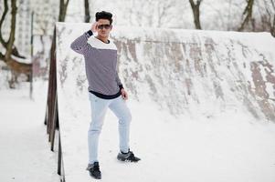 jeune homme indien décontracté à lunettes de soleil posé à la journée d'hiver. photo