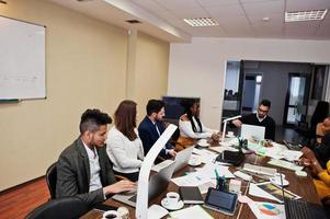 jeunes créatifs multiraciaux dans un bureau moderne. groupe de jeunes gens d'affaires travaillent avec un ordinateur portable, une tablette. équipe de pigistes à succès dans le coworking. photo