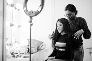 femme afro-américaine appliquant un coiffeur ou un coiffeur au salon de beauté. photo
