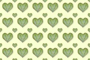 feuilles vertes en forme de coeur motif sans couture sur fond jaune clair. la notion d'amour. photo