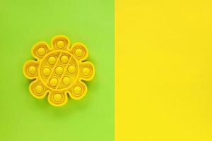 fleur jaune nouveau jouet à bulles de silicone sensoriel anti-stress à la mode sur fond de papier vert et jaune d'été. éclatez-le, poussez, pressez. pour petits et grands, détente, éducation, inspiration. photo