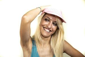 fille blonde au chapeau rose sourit les mains sur le chapeau rose photo