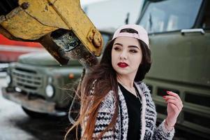 fille décontractée élégante brune en cap contre la vieille grue de camion. photo