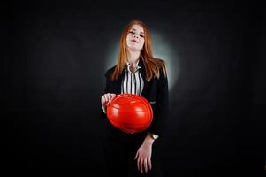 femme ingénieur en casque de protection orange sur fond noir de studio. photo