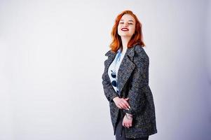 portrait d'une fantastique fille rousse en chemise bleue, pardessus gris posant avec des lunettes de soleil en studio. photo