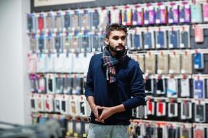 L'acheteur client de l'homme de barbe indien au magasin de téléphonie mobile choisit un étui pour son smartphone. concept de peuples et de technologies d'asie du sud. magasin de téléphonie mobile. photo