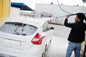 homme sud-asiatique ou homme indien lavant son transport blanc sur le lave-auto. photo