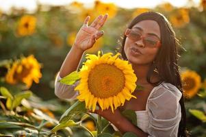 jolie jeune femme noire porte une robe d'été pose dans un champ de tournesol. photo