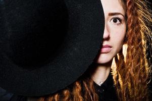 tournage en studio d'une fille en noir avec des dreads et un chapeau sur fond de briques. photo