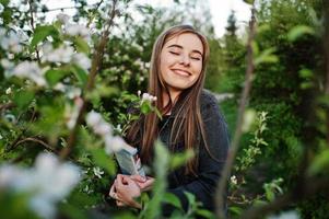 jeune fille brune en jeans contre l'arbre de fleurs de printemps avec livre. photo