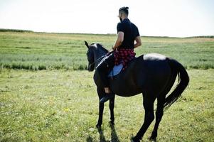 barbe haute arabe homme porter en noir et lunettes de soleil ride cheval arabe. photo