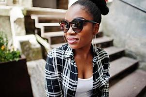 fille afro-américaine hip hop sur des lunettes de soleil et un short en jean. portrait de mode de rue décontracté de femme noire. photo