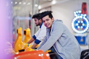 deux gars asiatiques s'affrontent sur la machine de simulateur de course de moto de jeu d'arcade de speed rider. photo