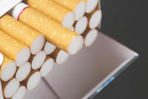 décollez-le du paquet de cigarettes préparez-vous à fumer une cigarette. ligne d'emballage. la photo filtre la lumière naturelle.