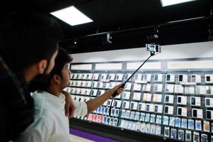 deux indiens mans client acheteur au téléphone mobile faisant selfie par bâton monopode. concept de peuples et de technologies d'asie du sud. magasin de téléphonie mobile. photo