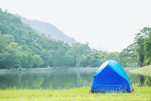 camping tente bleue en forêt près de la rivière du lac le matin ambiance rafraîchissante. voyage conceptuel. photo