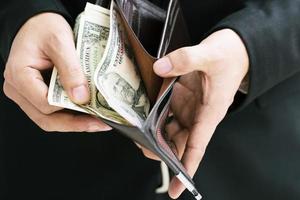 un homme d'affaires tenant un portefeuille entre les mains d'un homme sort de l'argent de sa poche. photo