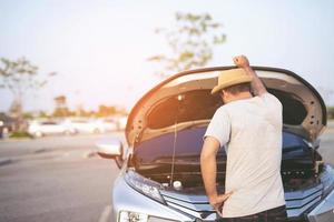 un jeune homme stressé ayant des problèmes avec son accident de salle des machines de voiture cassée par le stress à un moteur en panne attend de l'aide. photo