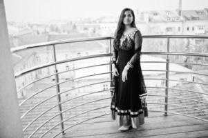 jolie fille indienne en robe sari noire posée au balkony. photo
